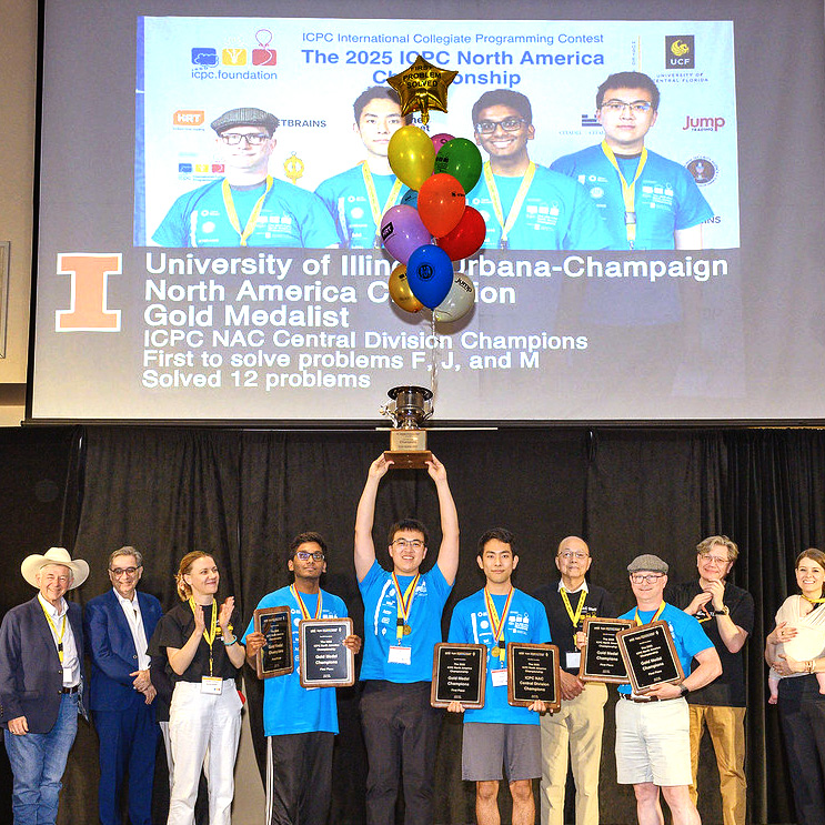 People stand on a stage, hold up a trophy, and show off their awards.