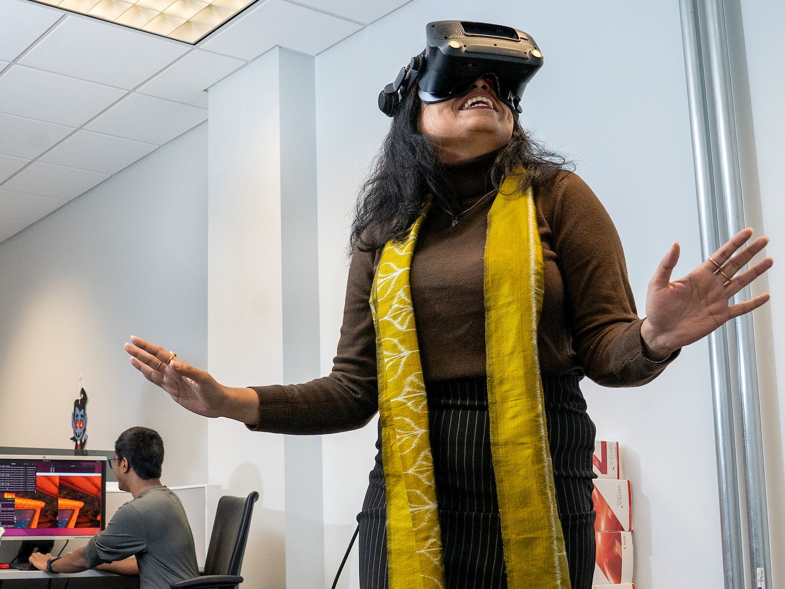 Three people in a room, one wears a VR (virtual reality) headset