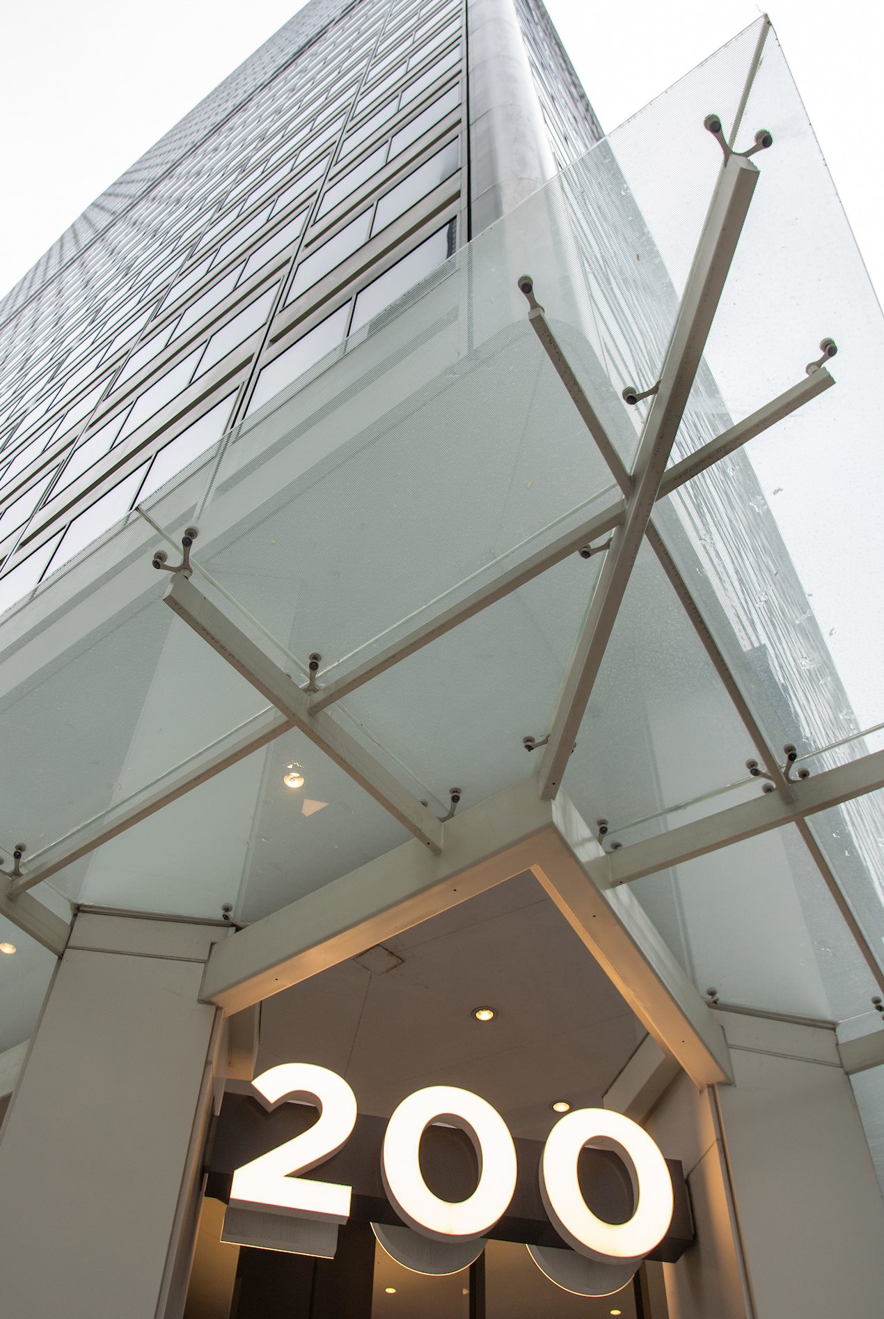 A front entrance with the number 200 of a white high-rise.