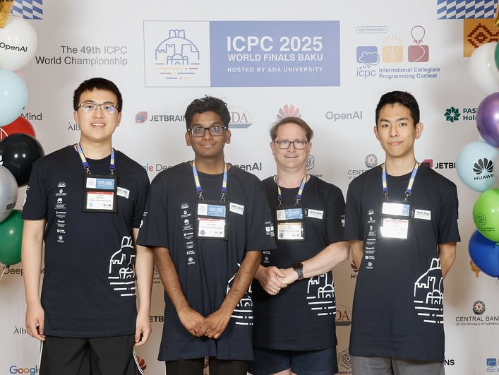 Three students and a professor stand in front of a 2025 ICPC poster near balloons.