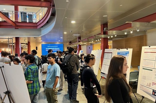 AICE fall 2025 syposium participants and passersby take in the poster session.