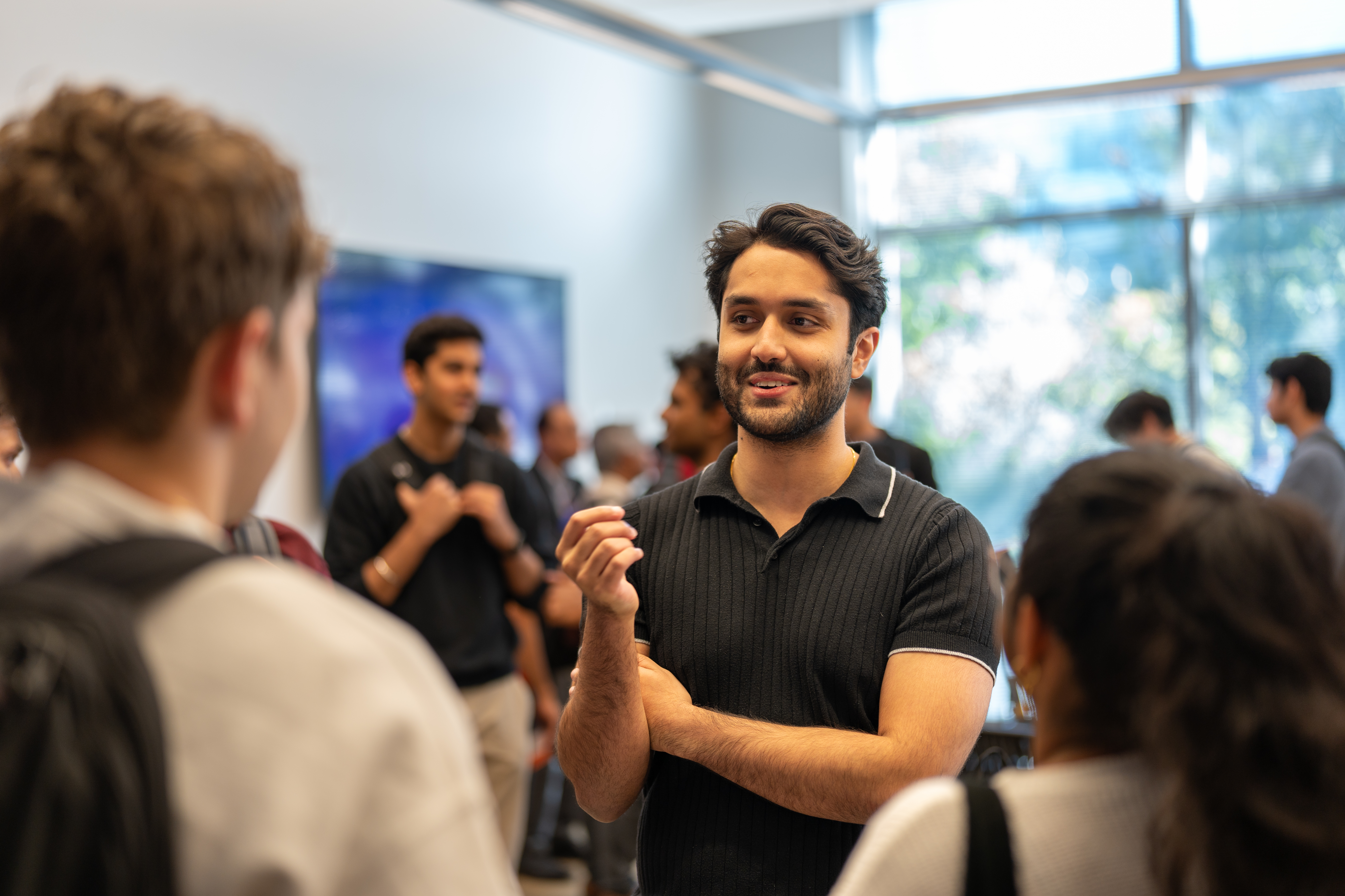 A person smiles and talks to a crowd of people surrounding them