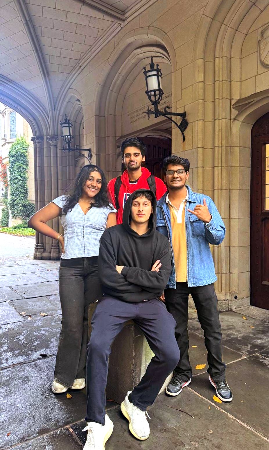 Four people smile under a gothic arch.