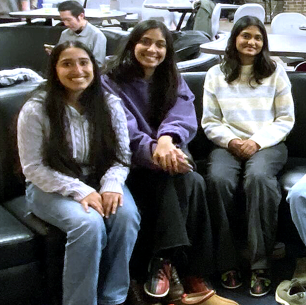 Three people sit and smile