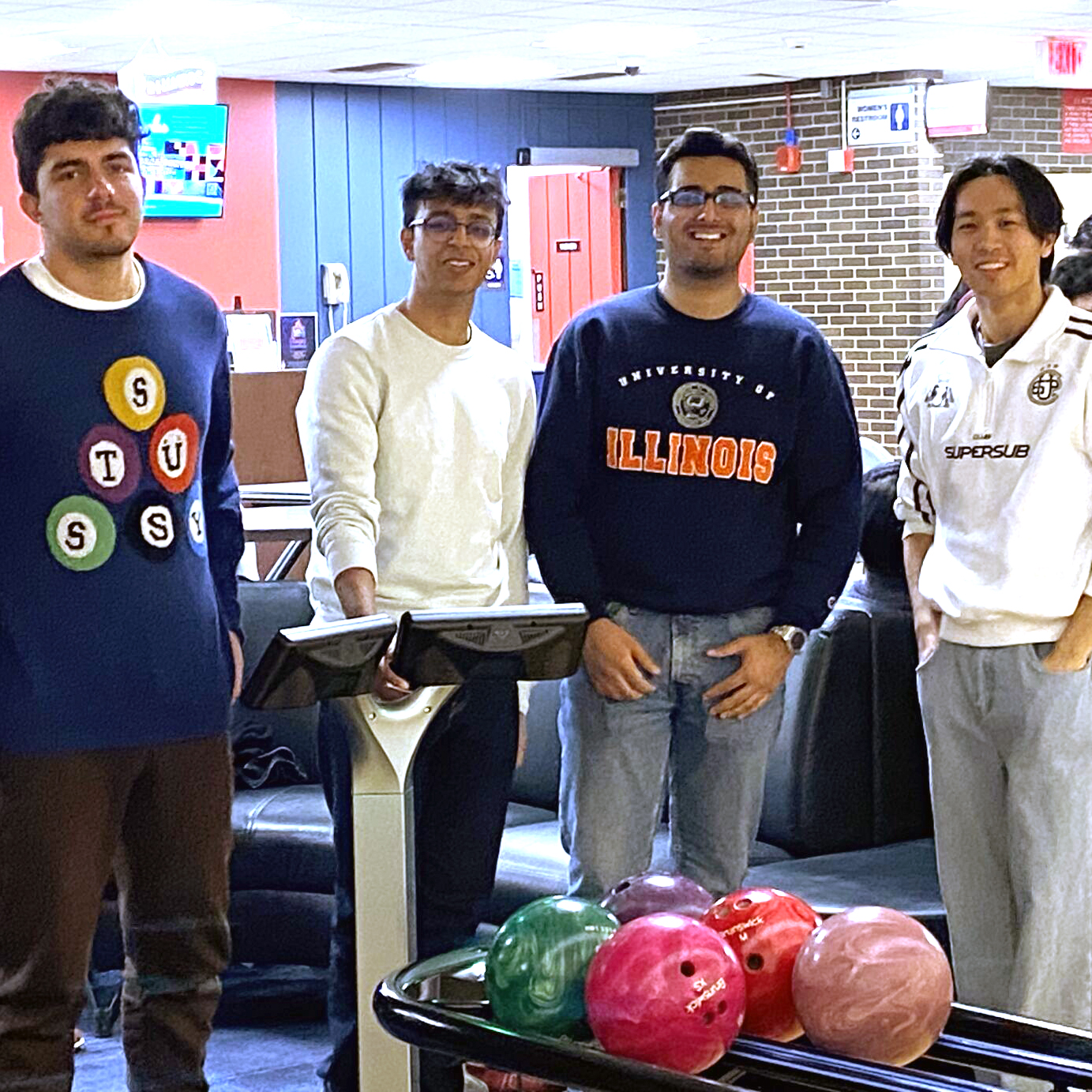 People stand and smile in front of bowling balls