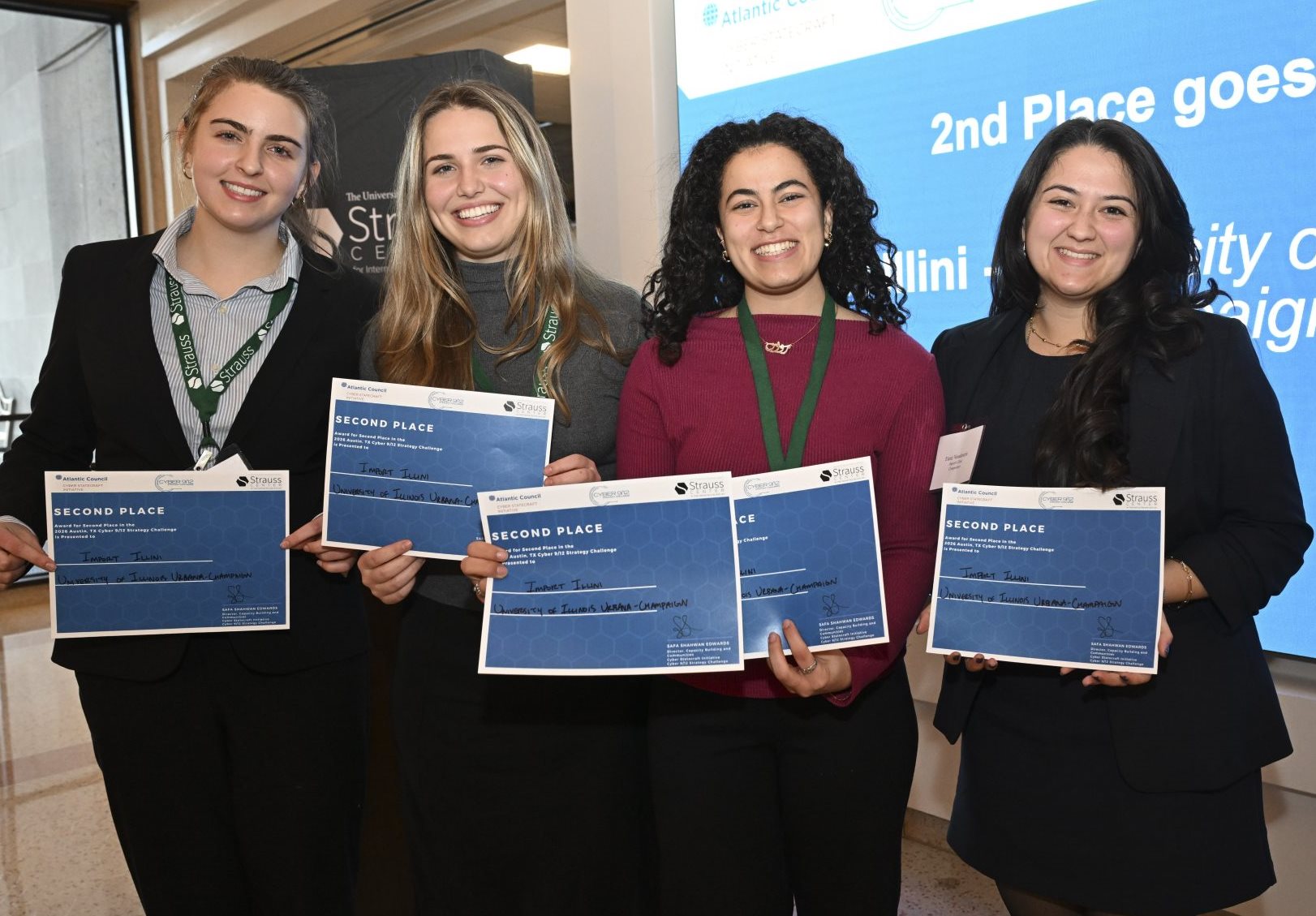 Four people hold certificates and smile