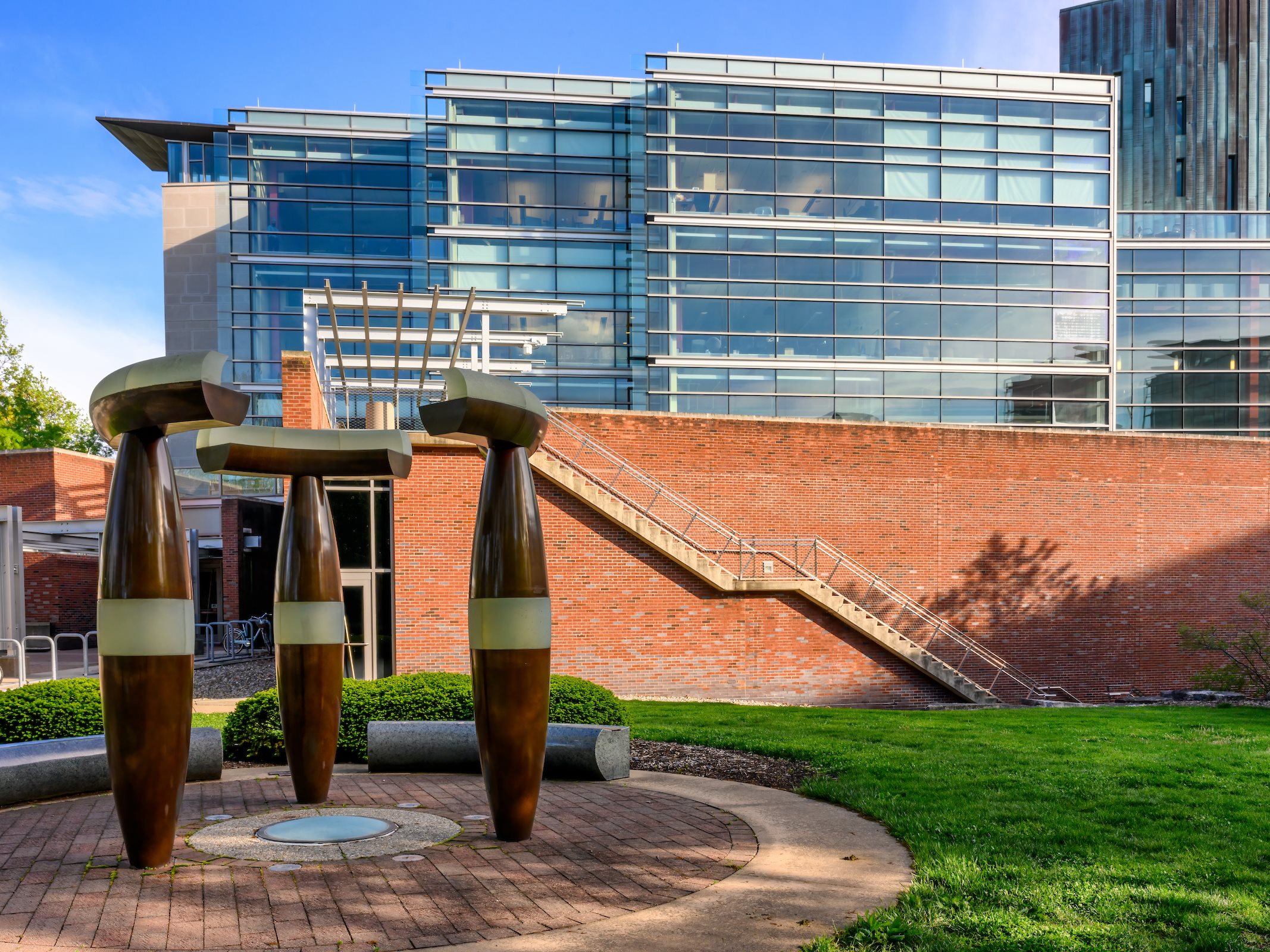 Exterior of a glass and brick building with a mushroom-like sculpture in front of it.