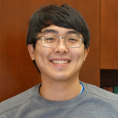 A man with black hair wearing glasses is smiling