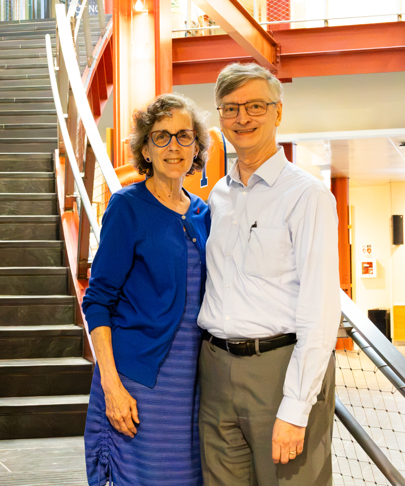 Two people stand in front of stairs.