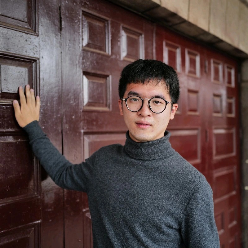 Man stands next to door with his hand on door