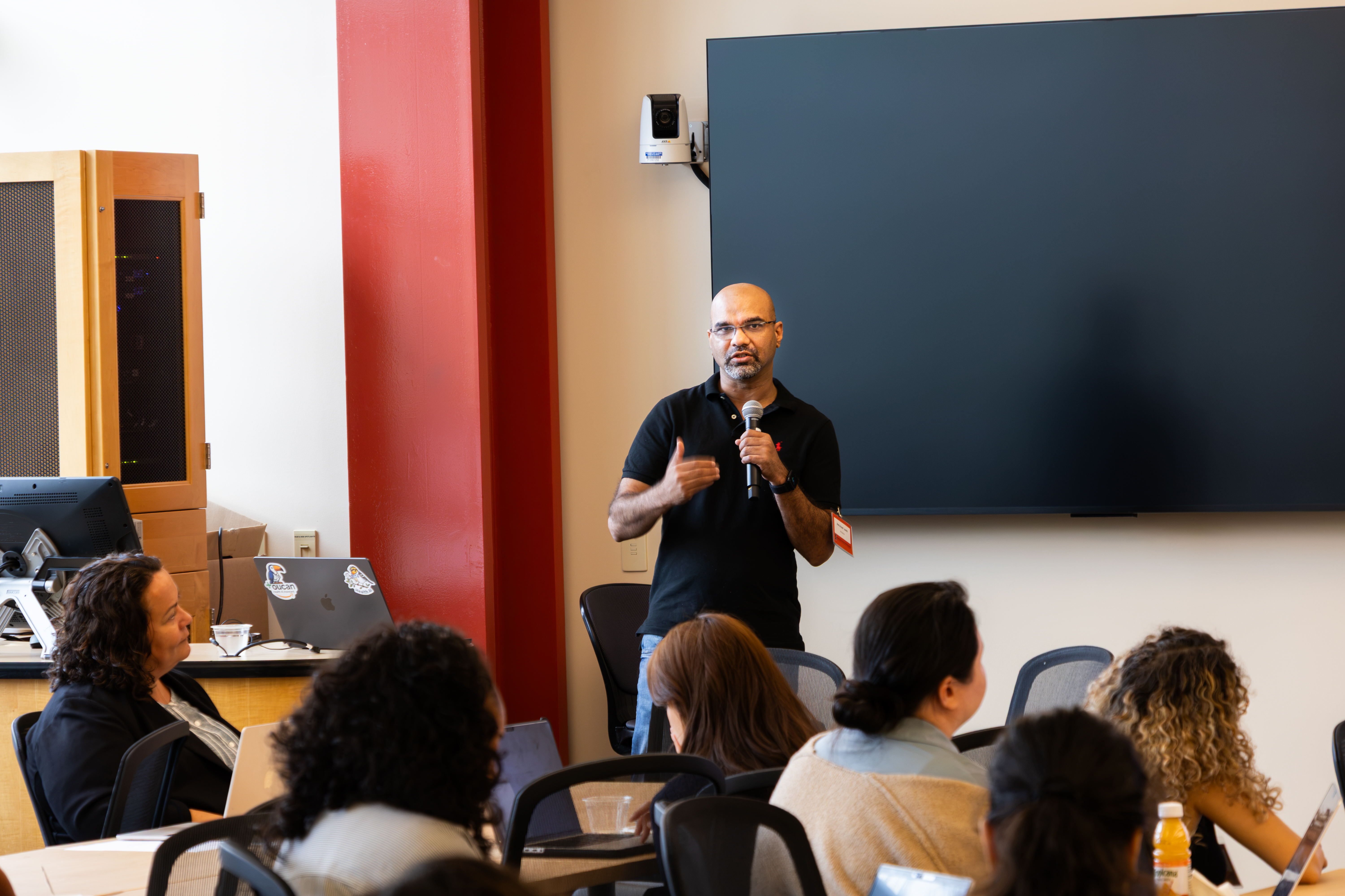 A man holds a microphone and speaks to an audience