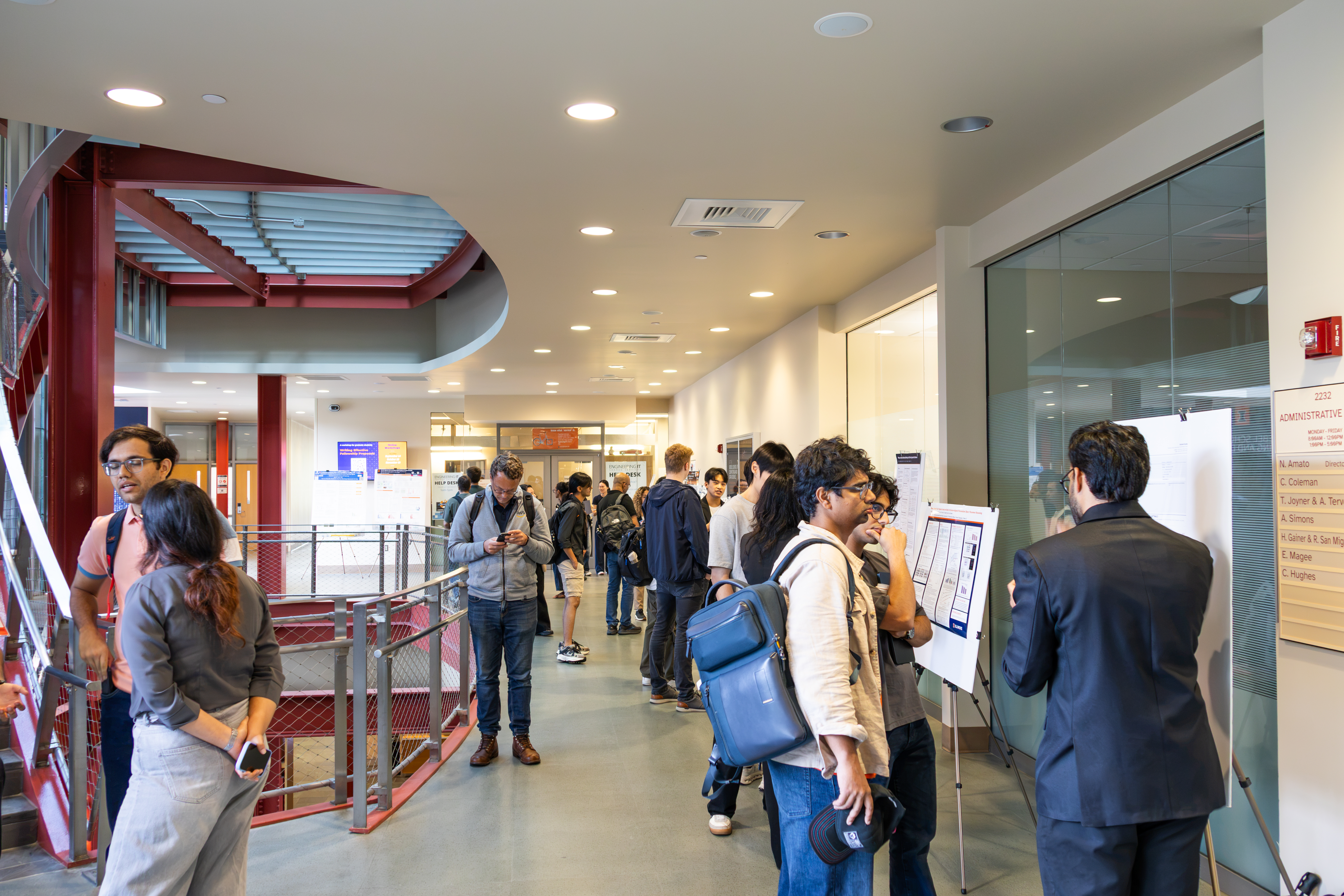 People line a hallways looking at posters