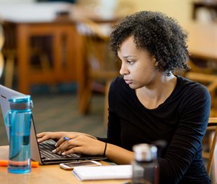 Woman at work station with laptop, notepad and cell phone