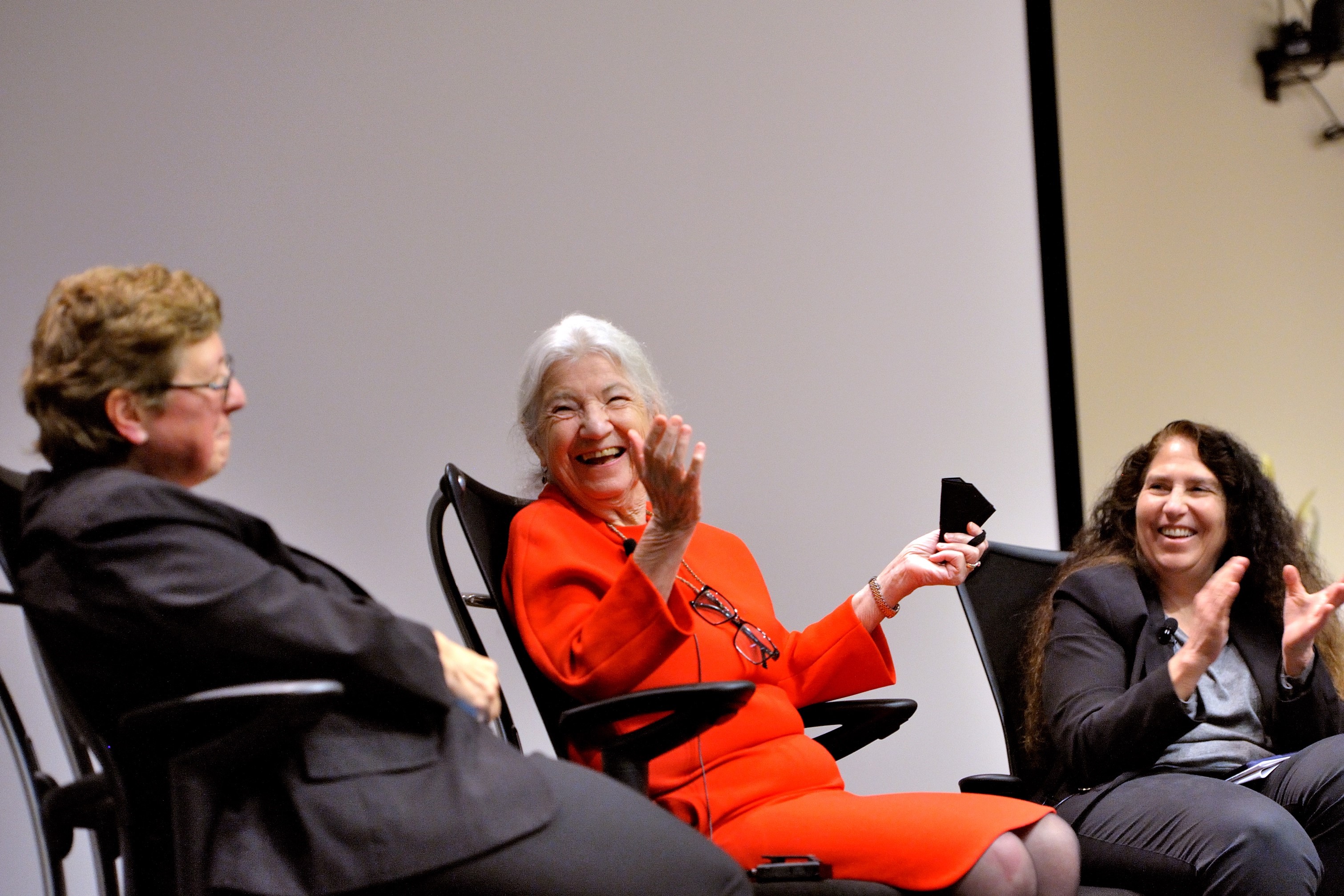 Three woman talk on stage and laugh.