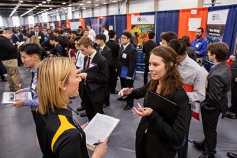 People in business clothes stand and talk to potential employers.