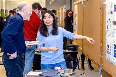 Two people look at and talk about a research poster.