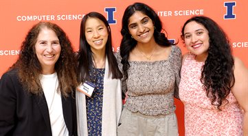 People pose in front of an orange banner at the 2024 Computer Science Celebration of Excellence