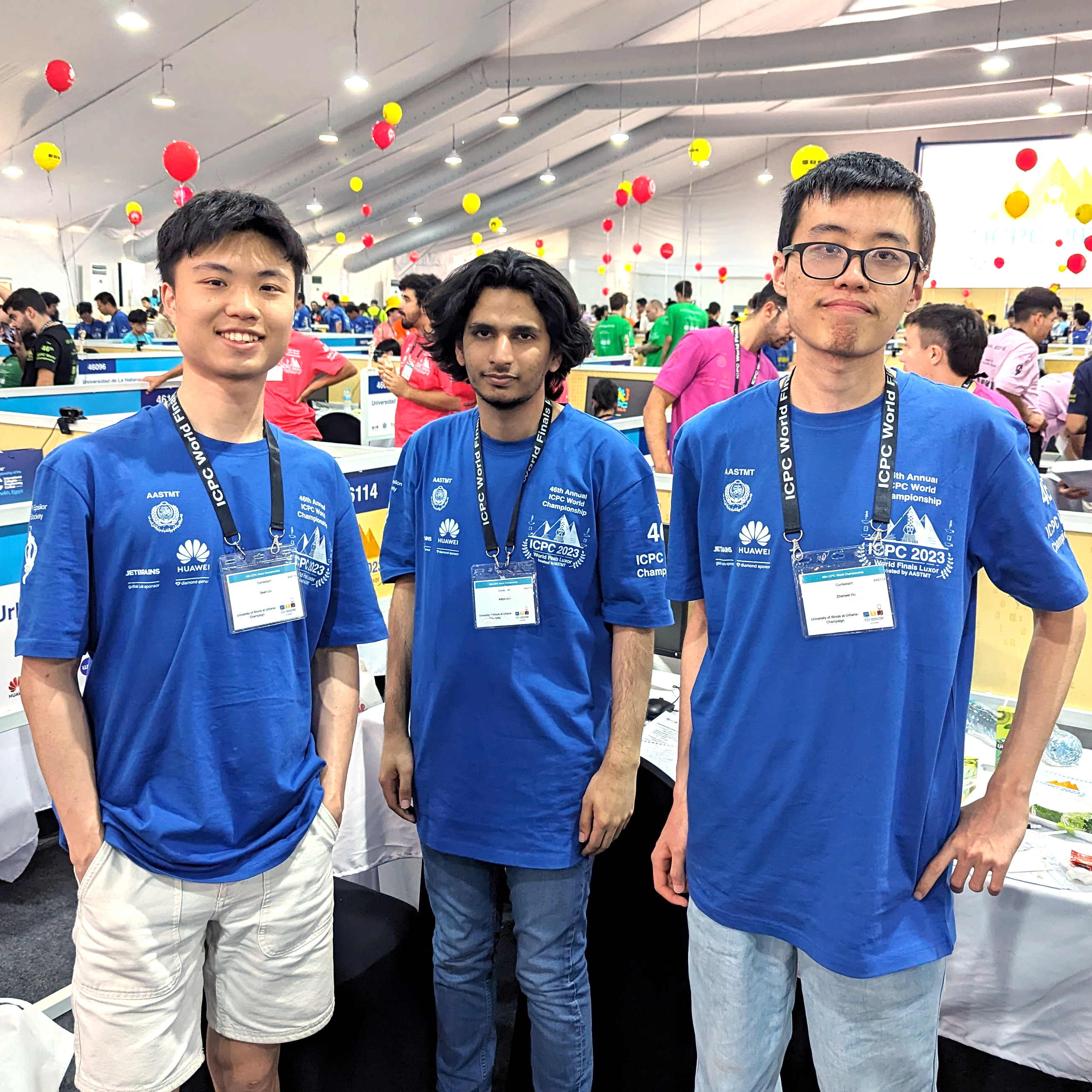 Three members of CS Team Ippatsu in blue shirts stand and look at the camera in a large, bright room on April 18, 2024, in Luxor, Egypt, at the International Collegiate Programming Competition where they won 70th place in the ICPC World Finals.