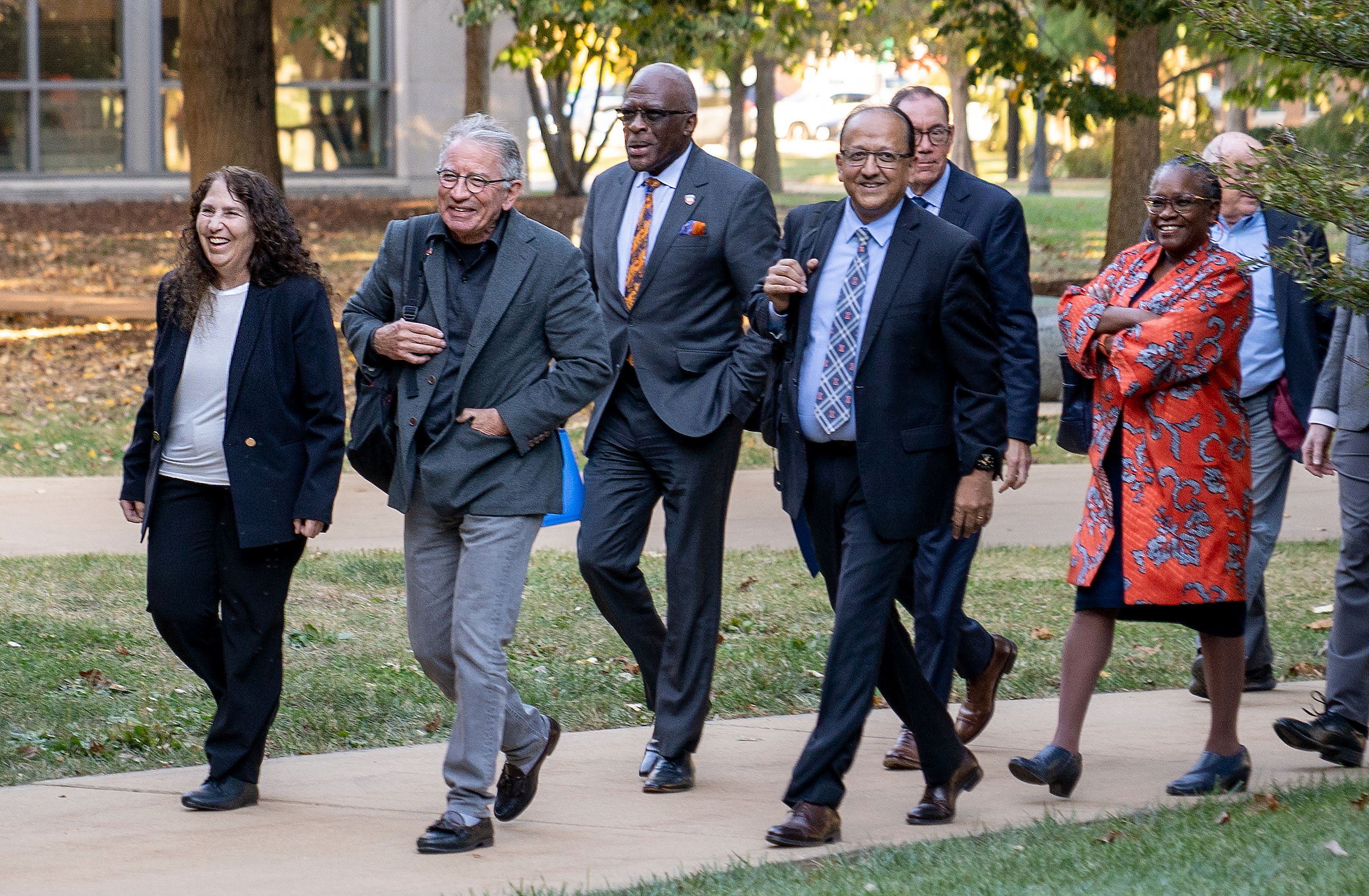 A large group of people smile and walk together. 