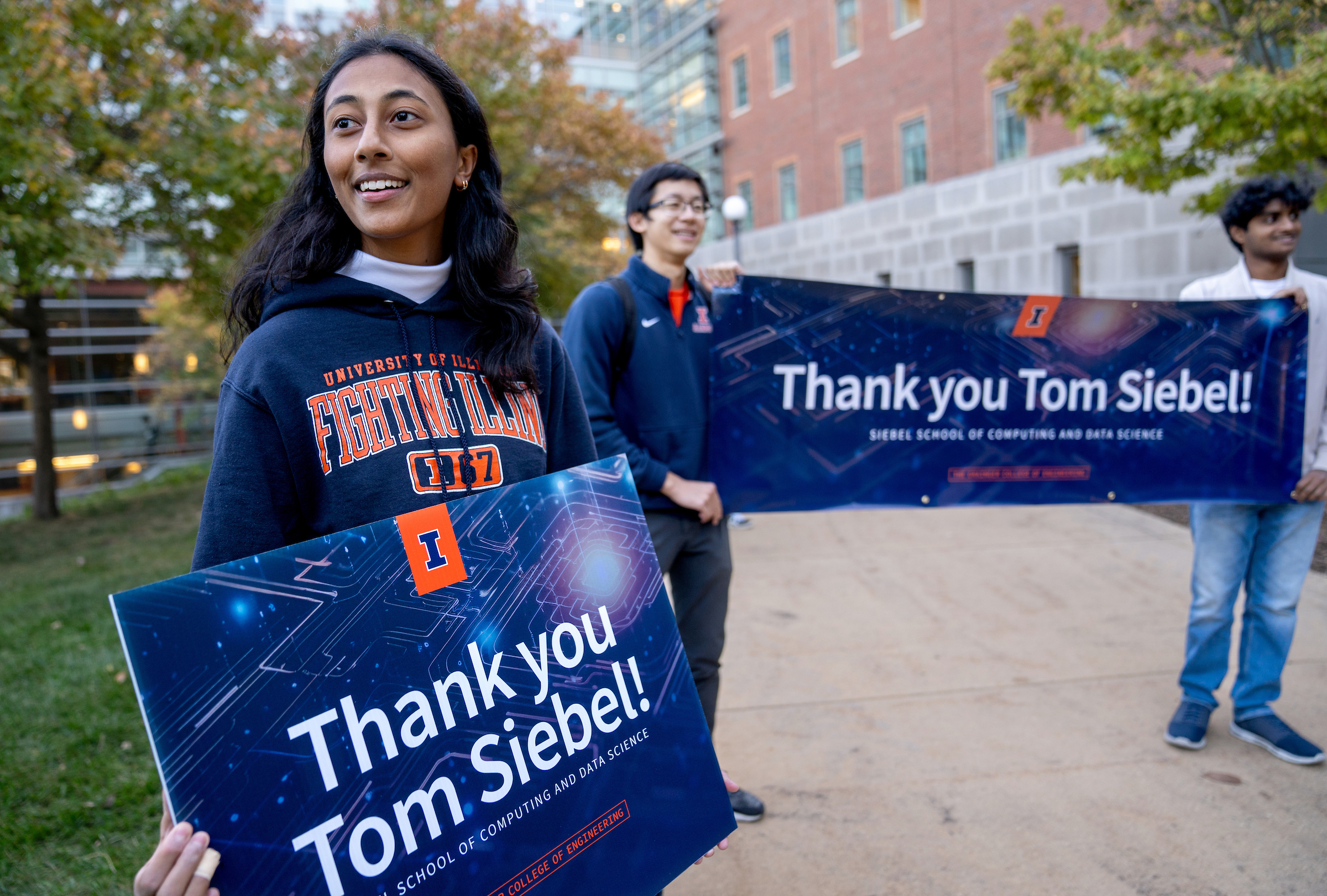 Students hold a sign and a banner and smile.