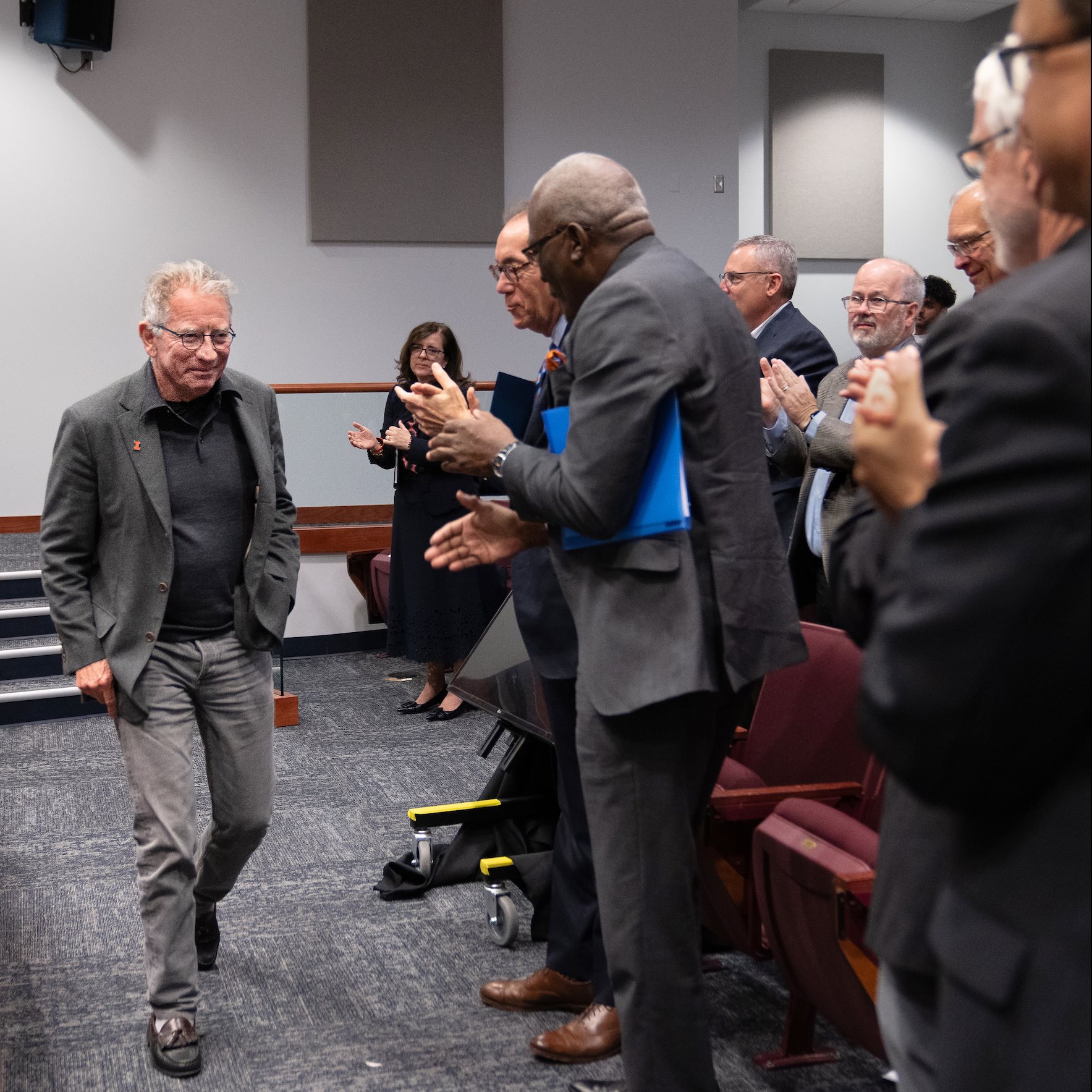 A man walks by people clapping.